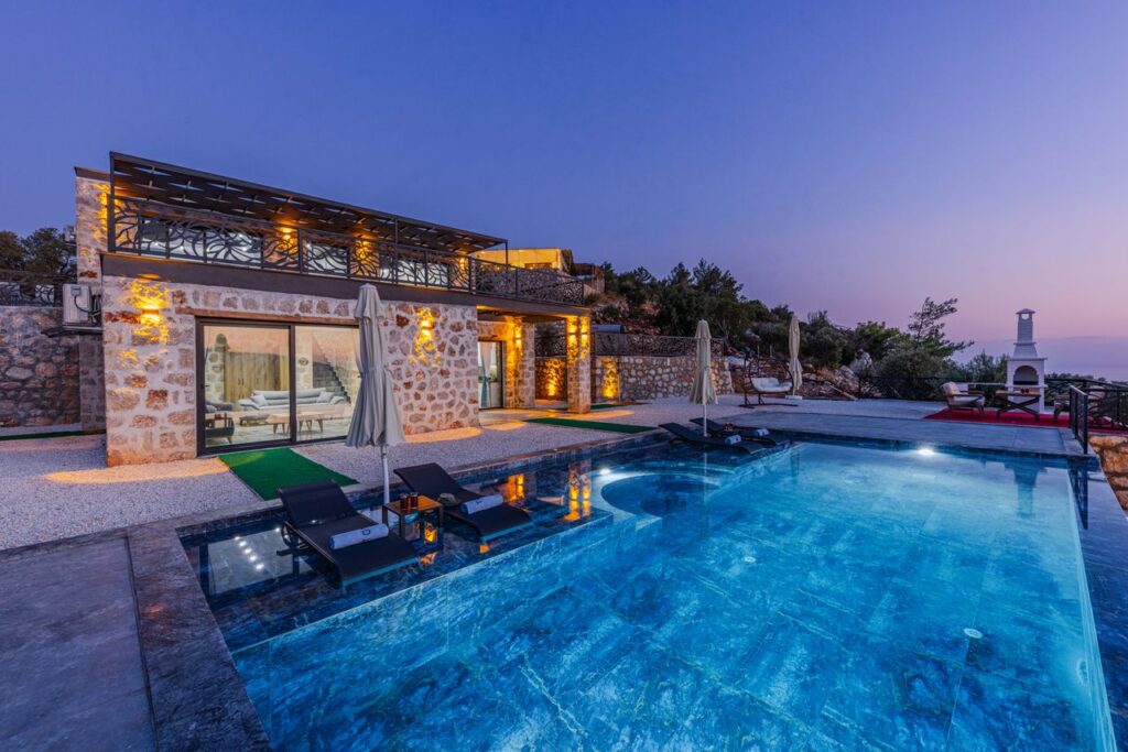 Elegant stone villa with infinity pool offers serene vacation vibes at twilight.